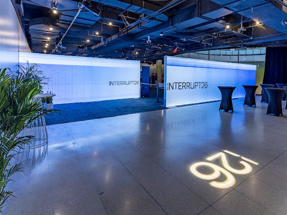 The Interrupt26 venue floor with lit Interrupt26 walls and the 26 logo projected on the floor